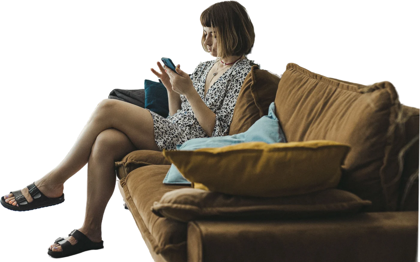 Une patiente assise sur son divan, à la maison, lit un texto sur son téléphone